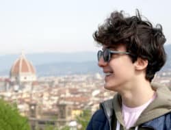 Smiling student with backpack in Florence, with the Duomo in the background, symbolizing the return to school and university life in Tuscany.