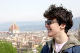 Smiling student with backpack in Florence, with the Duomo in the background, symbolizing the return to school and university life in Tuscany.