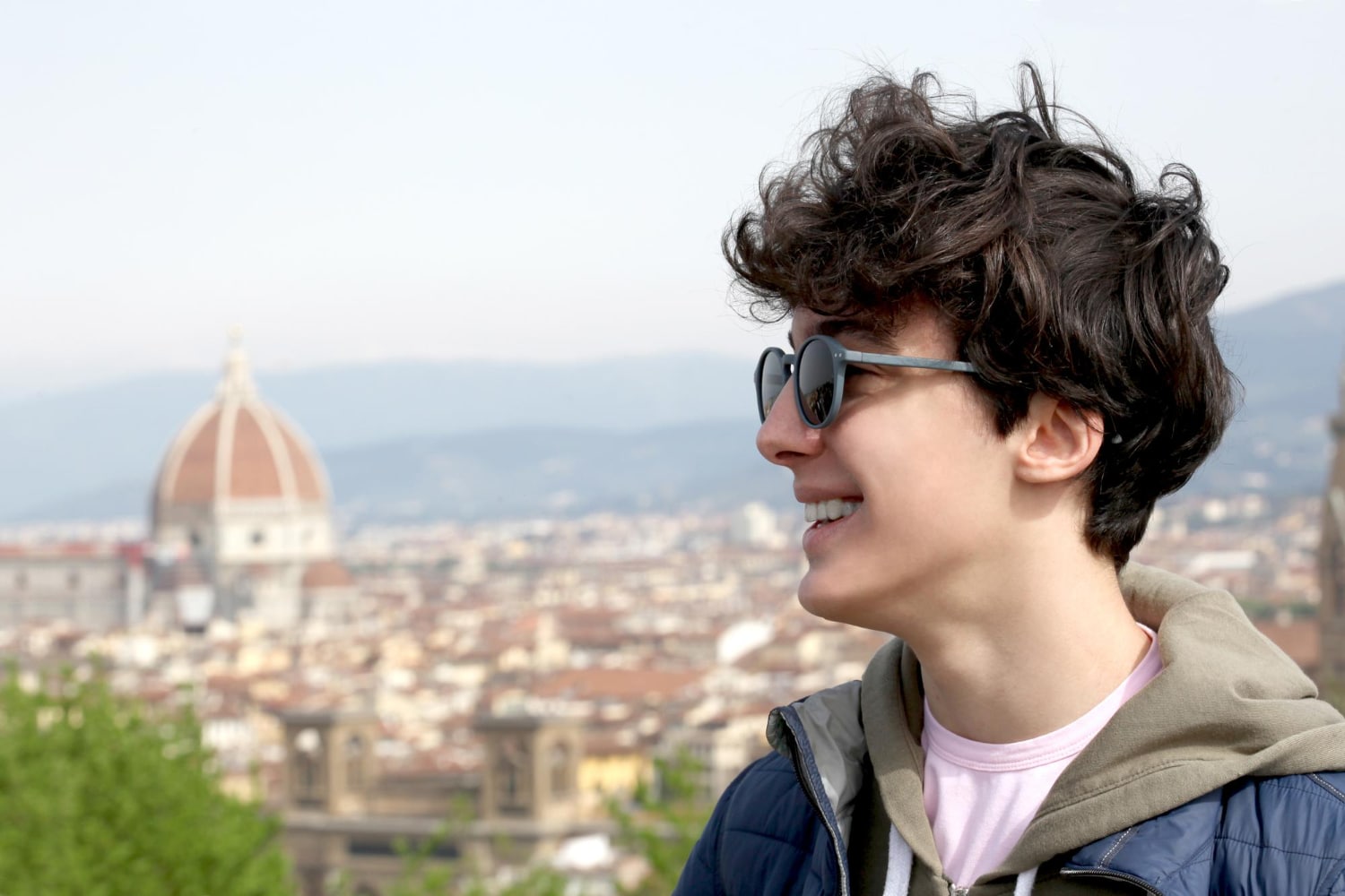 Smiling student with backpack in Florence, with the Duomo in the background, symbolizing the return to school and university life in Tuscany.